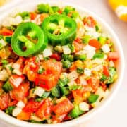 Homemade Pico de Gallo in a white bowl garnished with sliced jalapeño.