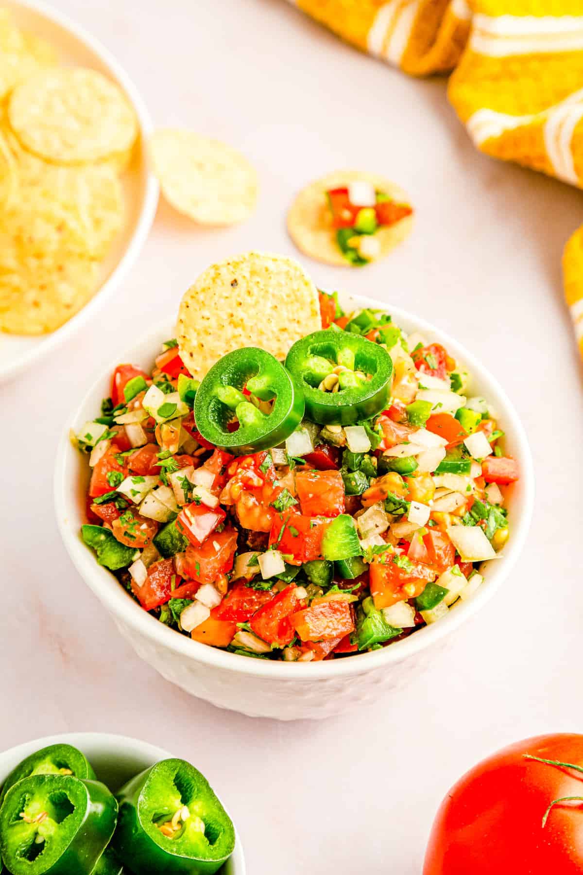 Homemade Pico de Gallo in a white bowl garnished with sliced jalapeño.
