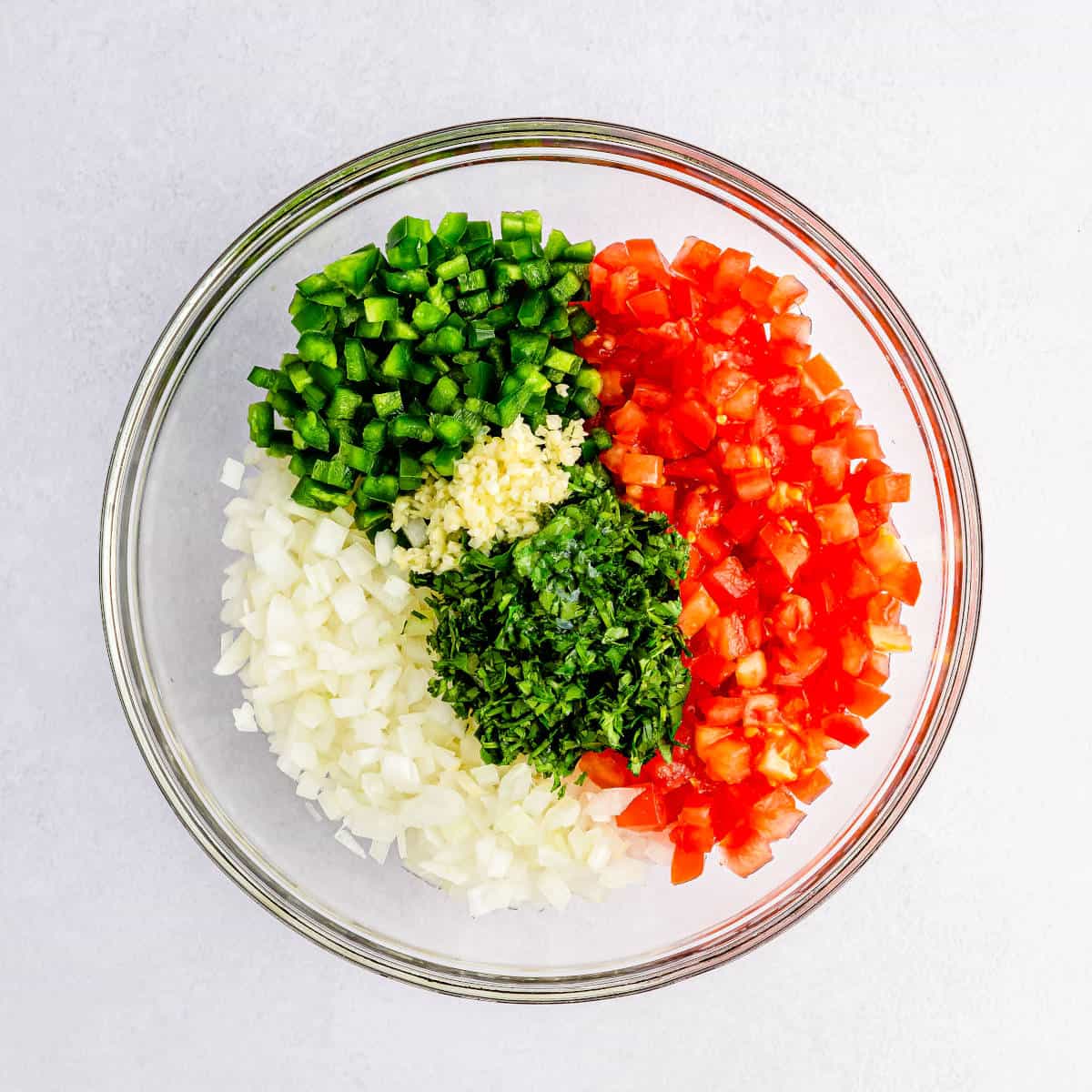 Pico de Gallo ingredients added to a medium glass mixing bowl.