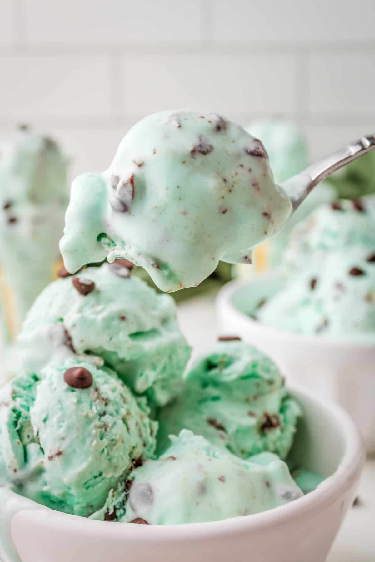 Green no-churn ice cream being spooned out of a white bowl.