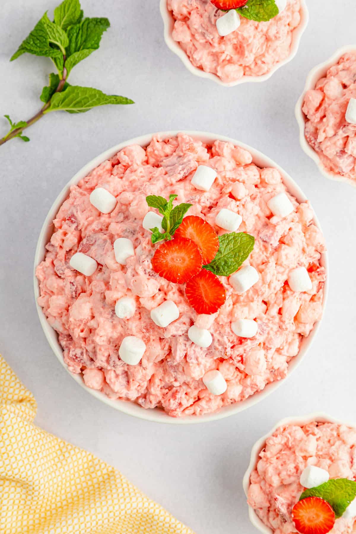 Strawberry fluff salad in a white bowl and topped with extra marshmallows.