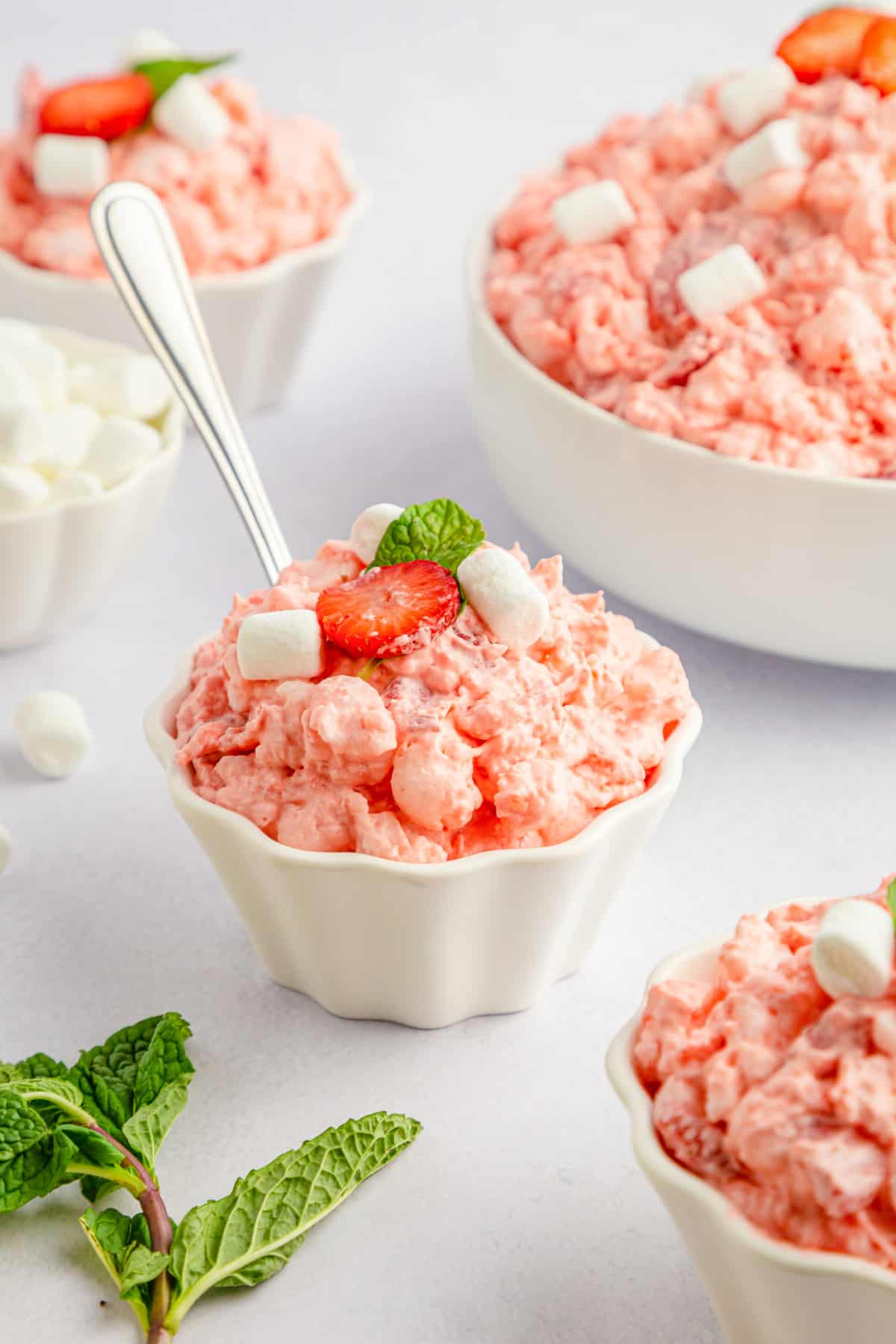 Strawberry marshmallow fluff in a small white bowl with a silver spoon.