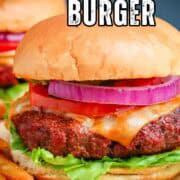 A pellet grill burger with tomato, onion, and lettuce on a sheet of brown parchment paper.