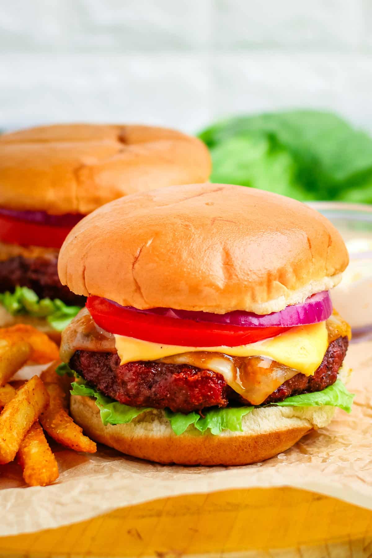 A cheeseburger cooked on a pellet grill with a side of fries.