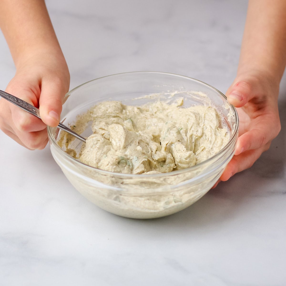 Stirring the ingredients for the garlic and herb butter rub in a small glass bowl.